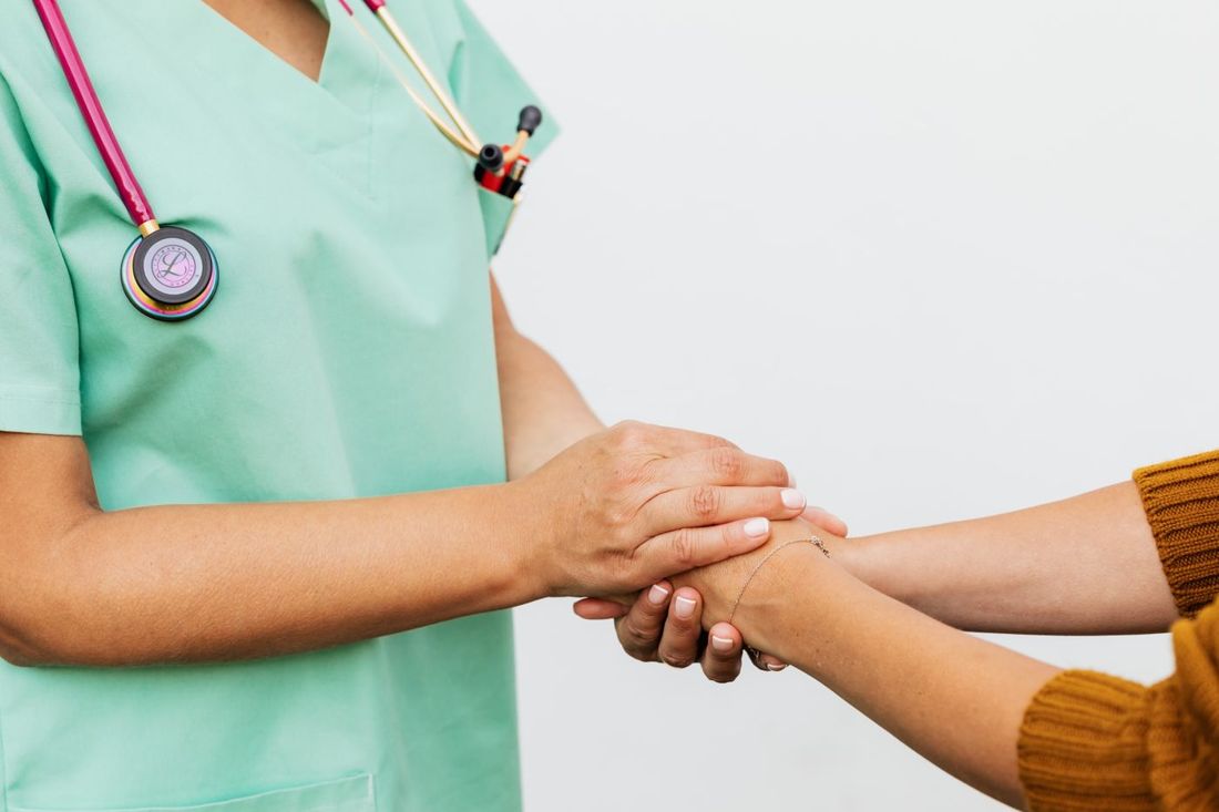 A nurse gently holding a patient's hands in both of hers